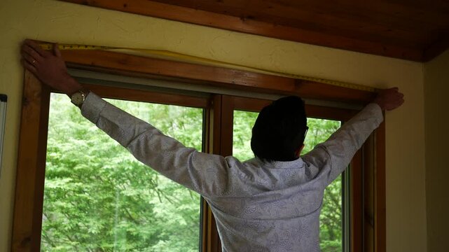  A Man or Contractor Measures a Large Window - Angle 2