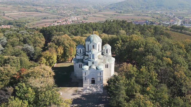 Aerial view of Saint George Church on Oplenac hill with lateral drone movement over green treetops, Sumadija, central Serbia.