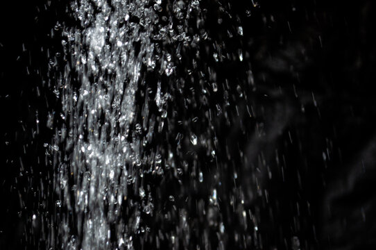 Water spray creates droplets in a dark background during the evening
