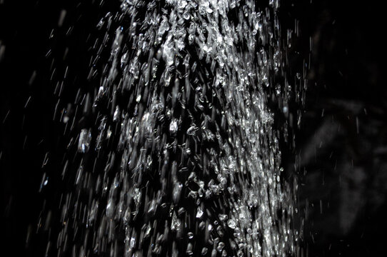 Water spray creates droplets in a dark background during the evening