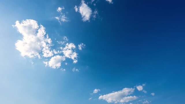 Time lapse of White clouds moving slowly across blue sky. Cloud formation creating natural atmospheric background with soft white patterns and changing light conditions.