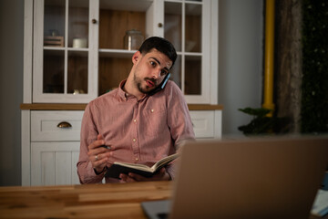 Fototapeta premium Man multitasking working from home using laptop and phone