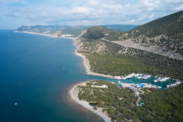 Obraz premium An aerial view of the winding Black Sea coastline in the village of Bolshoy Utrish, with a yacht mooring in the waters of Lake Zmeinnoye and yacht club infrastructure.