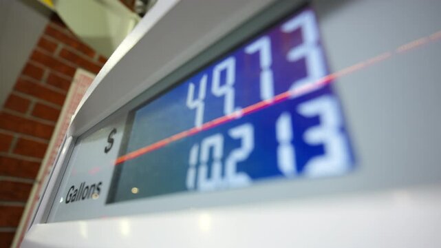 Gas station pump display showing fuel price and gallons during car gas refueling process.