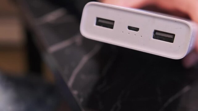 Close-up of a hand unplugging a micro USB cable from power bank, showing portable charging device usage, power disconnection and everyday mobile energy management. Disconnecting cable from power bank