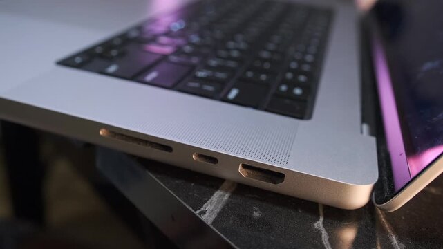 Close-up of removing a USB-C cable from a laptop port, showing device disconnection, modern data transfer interface and everyday workflow with portable computer hardware and external accessories 