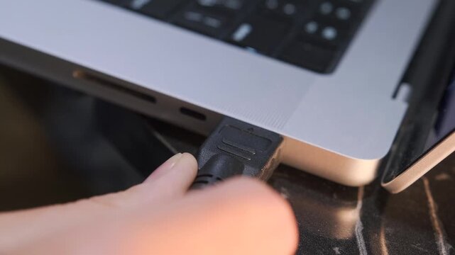 Close-up of inserting an HDMI cable into a laptop port, showing video signal connection, external display setup and modern digital interface usage for screen sharing and multimedia output