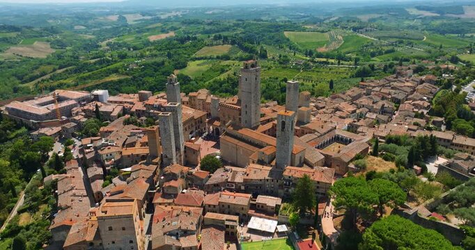 San Gimignano Italy medieval architecture drone shot. High density stone buildings red rooftops summer atmosphere. Aerial cityscape Tuscany region tourism landmark exploration heritage site high angle