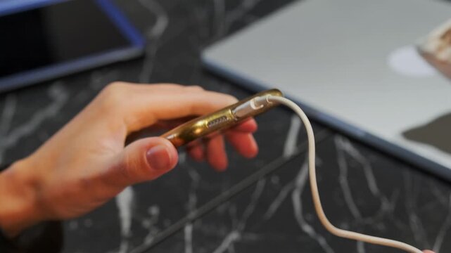 Close-up phone inserting Lightning cable into smartphone port, showing mobile device charging, data connection and everyday interaction with modern digital gadgets and portable electronics accessories