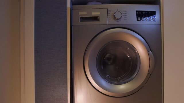 washing machine spinning clothes front view, high speed drum rotation in turbo mode, intense cycle removing water from fabric, household appliance operation, efficient laundry process at home