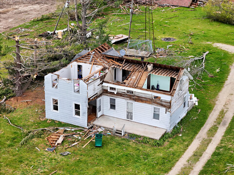 Tornado damaged two story home with roof loss and exterior debris.