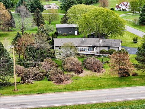 Residential property showing post storm straight line wind damage to trees and sun porch on home