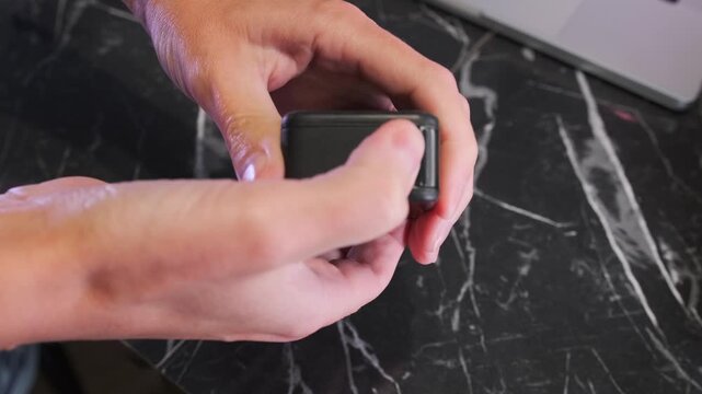 Close-up of hands removing a battery from an action camera slot, demonstrating device maintenance, power replacement and preparation for further use in portable video equipment