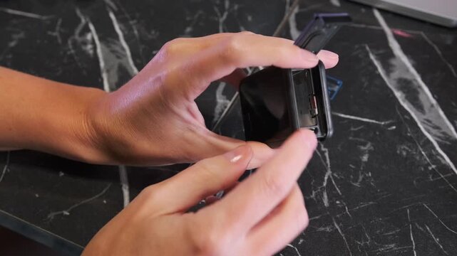 Hand removing memory card from action camera slot, close-up of storage access and device maintenance, user extracting micro SD card for data transfer or replacement indoors