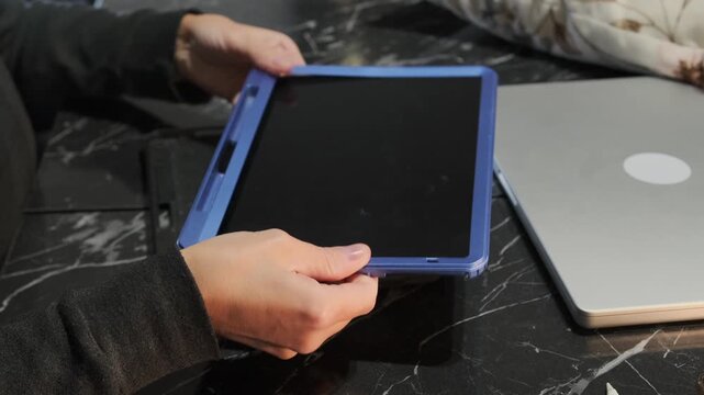Close-up of hands putting armored protective case on tablet, securing device from damage, enhancing durability and safety, everyday gadget protection and mobile device care at home or office