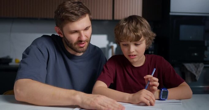 Father Teaches Son Handwriting Skills. Dad Patiently Instructs Boy On Proper Handwriting Techniques