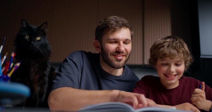 Father And Son Celebrate Achievement. Happy Family Bonds As Child And Father Smile Together With Cat