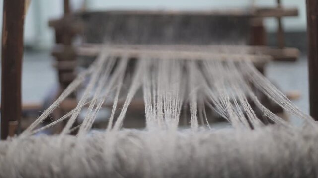 A close-up shot of a weaving machine with yarn wound around the frame, ready for use
