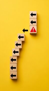 Wooden blocks with arrows pointing to warning sign on yellow background