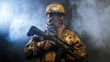 Naklejka premium Armed soldier in combat uniform holding weapon on black background with smoke. Concept warfare and readiness. 