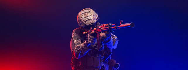 Naklejka premium Soldier in combat gear on abstract red and blue blurred backdrop. Concept readiness and discipline. 