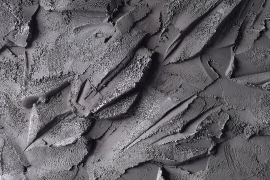 Close-up of rough gray cement or plaster surface with irregular strokes and patterns, creating a textured abstract background b.vv
