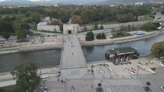 Aerial panning shot of the historic stone pedestrian bridge crossing the Nisava river in the center of Nis, Serbia. The bridge leads directly to the entrance of the medieval fortress.