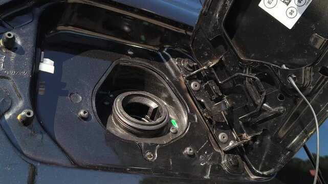 Close up of hand opening car fuel cap and unscrewing tank cover, preparing for refueling, vehicle exterior detail, gas station concept, automotive maintenance and operation