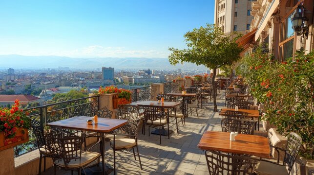 Cafe tables and chairs on a terrace overlook a stunning city view.