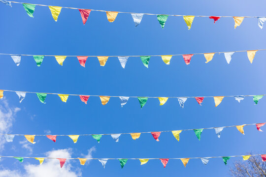 Colorful festive pennant flags against blue sky outdoors