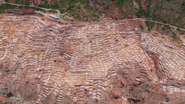 Aerial view of the Maras Salt Mines in Peru, showcasing vast salt flats and rugged mountain terrain