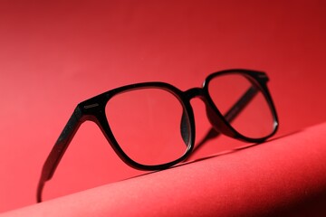 Pair of eyeglasses on red background, closeup