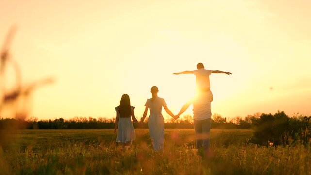 Picnic happy people outdoors. Happy family. Dad mom, kids in sunny park. Family walk on green grass, son sitting on dad's shoulders, mother daughter. Family in nature. Young family on lawn in summer
