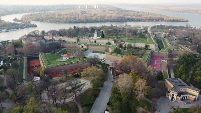 Cinematic aerial drone dolly shot moving sideways over the Kalemegdan fortress park in Belgrade, Serbia. Confluence of the Sava and Danube rivers are in the background, sunny day.