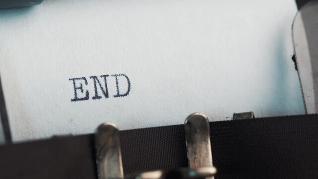 Words are finished with a typewriter showing the end of a story on paper in a close-up view