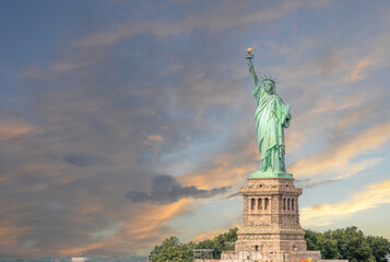 Fototapeta premium New york, usa august 16,2024. Statue of liberty at sunset over new york harbor, iconic symbol of freedom, immigration, hope and american ideals