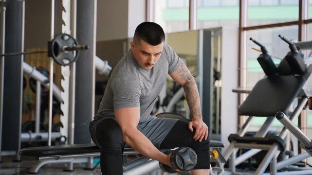 Muscular tattooed man performing dumbbell bicep curls