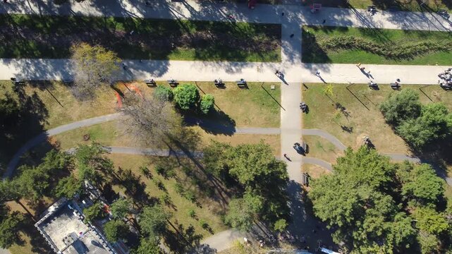 Cinematic top-down aerial shot of walking paths, lush green lawns, and trees in Tasmajdan park, central Belgrade, Serbia.