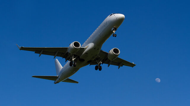 Passenger Airplane Landing with Moon in Clear Blue Sky Minimal Aviation Scene | Lądowanie samolotu pasażerskiego z księżycem na tle czystego, błękitnego nieba. Minimalistyczna scena lotnicza