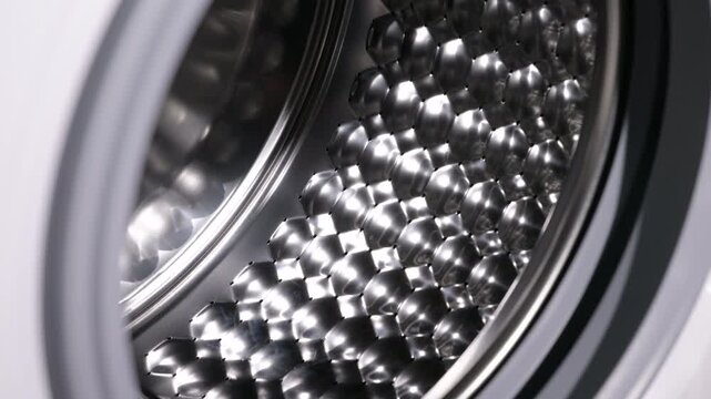Washing machine drum with honeycomb pattern. Macro shot slowly zooming into the empty and clean stainless steel drum of a modern washing machine, showing the details of its special honeycomb texture