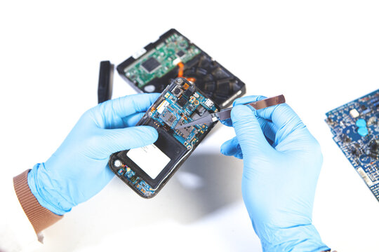 Disassembled smartphone in the hands of a repairman in blue gloves