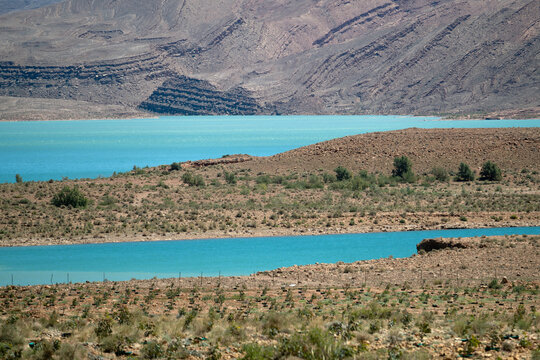 detail of turquoise waters of Hassan Addakhil reservoir contrast beautifully with the arid and rocky mountains of the High Atlas near Errachidia in Morocco under a bright blue sky, Barrage Hassan