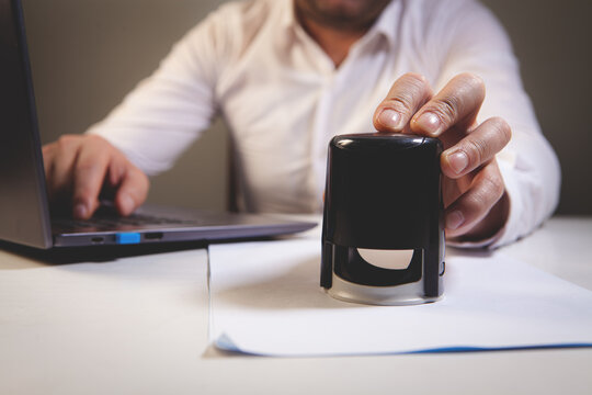 Man writing on paper at desk against black background with vignette