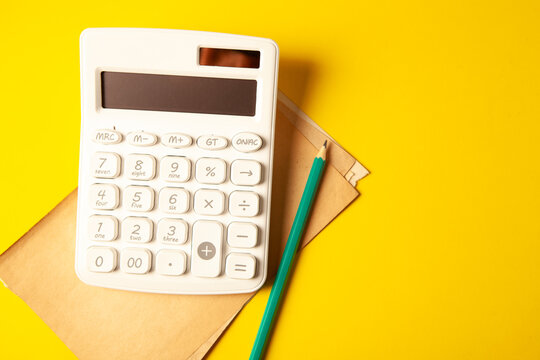 yellow calculator and pen on a yellow background