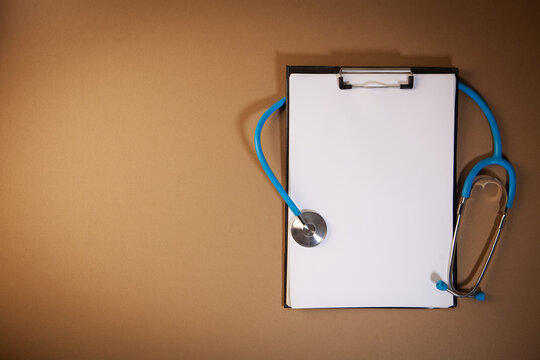 Stethoscope and clipboard on brown background. Copy space for text.