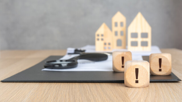 Wooden blocks with exclamation mark and blurred house models.