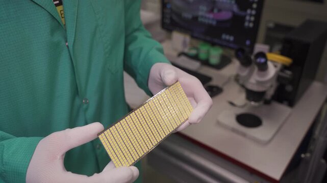 An LED panel with white diodes in the hands of an employee at an LED lamp and panel factory. Production and quality control of lighting equipment. High-tech LED panel assembly. Close-up.