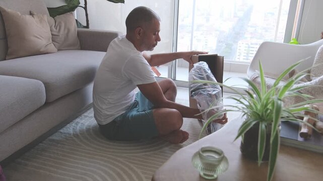 Future dad unboxing and assembling a baby high chair in the living room while preparing for newborn