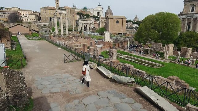 Fashion skylish female model walk visiting ancient Roman Forum in Rome, Italy, aerial drone view
