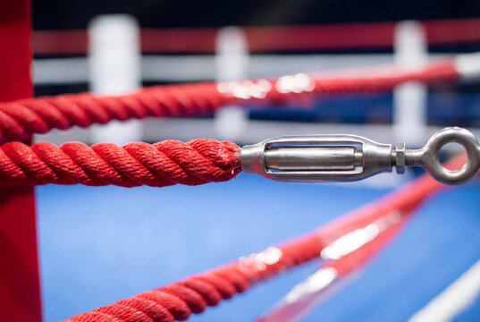 Close view of red boxing ring ropes and metal tensioner turnbuckle